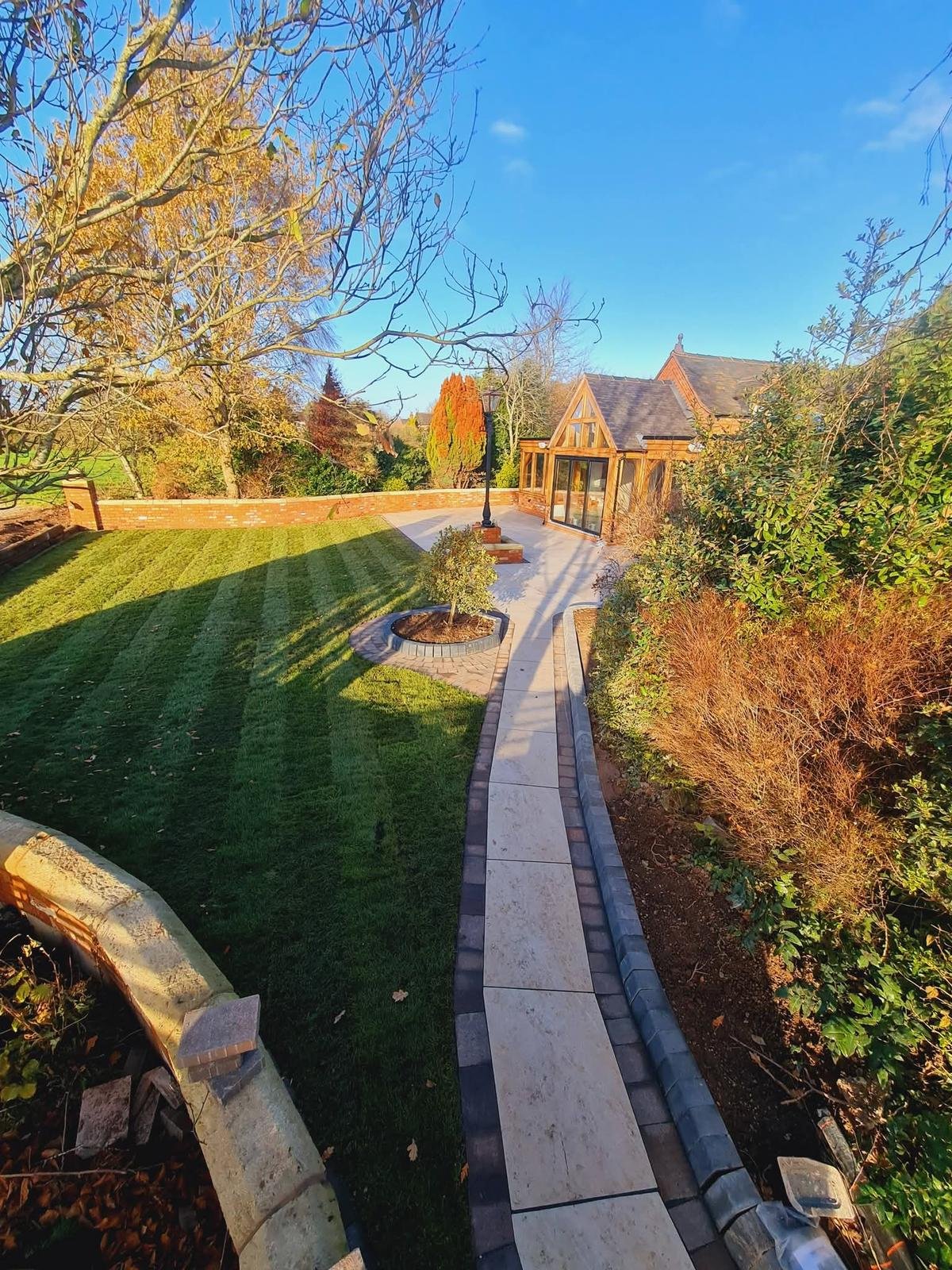 Landscaped garden with a shaped lawn, curved paved path and planted borders